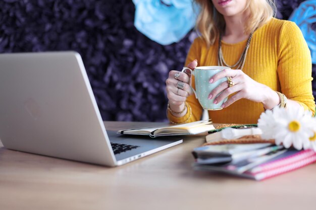 Jovem mulher em uma pausa para o café ou aproveitando a pausa para o café usando o computador portátil