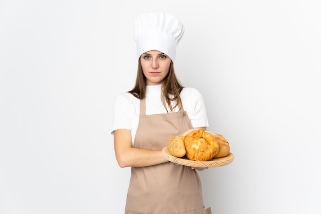 Jovem mulher em uniforme de chef isolado no branco, mantendo os braços cruzados