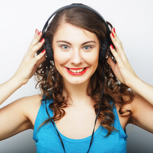 Foto jovem mulher encaracolada com fones de ouvido, ouvindo música.