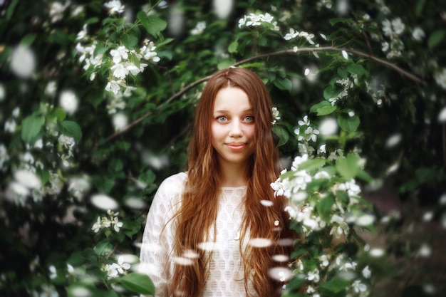 Jovem mulher entre as flores da primavera ao ar livre