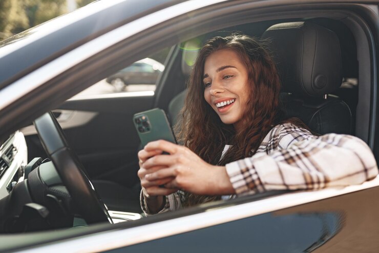 Foto jovem mulher enviando mensagens de texto em seu smartphone enquanto dirige um carro