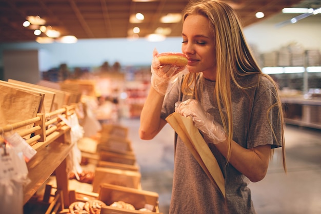 Foto jovem mulher escolhe pão na loja