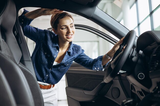 Jovem mulher escolhendo um carro no showroom de carros