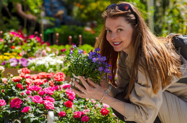 Jovem mulher escolher flor para comprar no jardim colorido de mercado aberto