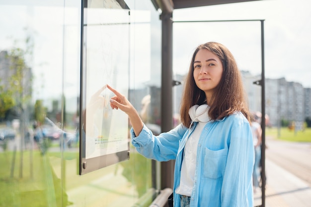 Jovem mulher esperando o transporte público em pé na moderna estação de bonde ao ar livre