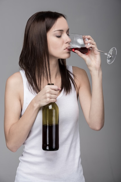 Jovem mulher está bebendo vinho, isolado