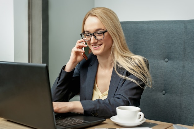 Jovem mulher está falando por telefone celular no escritório.