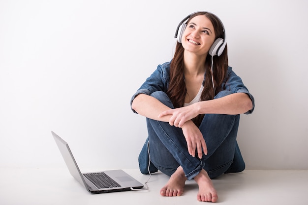 Jovem mulher está sentada no chão com o laptop.