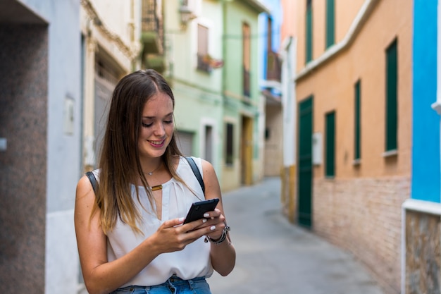 Jovem mulher está usando seu smartphone na rua