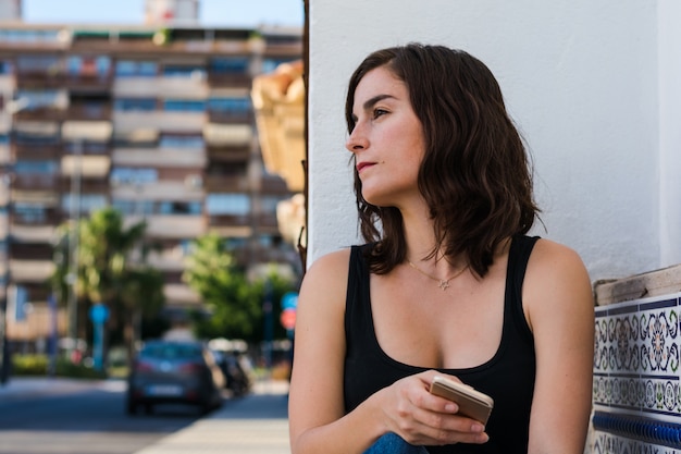 Jovem mulher está usando seu smartphone na rua