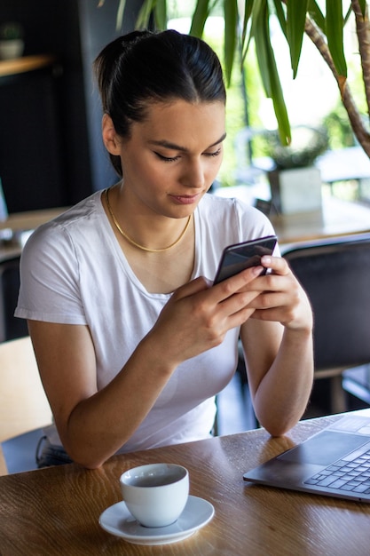 Jovem mulher europeia encantadora ligando com telefone celular durante o café da manhã em uma cafeteria bela estudante falando conversa no telefone móvel enquanto relaxa depois de palestras