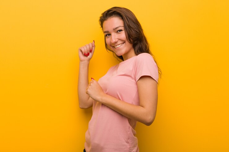 Foto jovem mulher europeia isolada em amarelo, dançando e se divertindo.