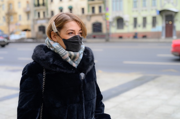 Jovem mulher europeia na máscara preta médica descartável protetora na cidade ao ar livre. proteção do conceito do perigoso coronavírus da influenza 2019-nCoV, mutado e disseminado na China