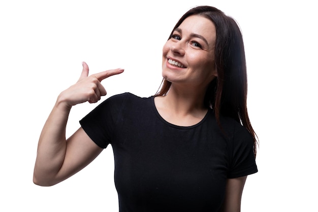 Jovem mulher europeia sorridente vestida com uma camiseta básica apontando com o dedo