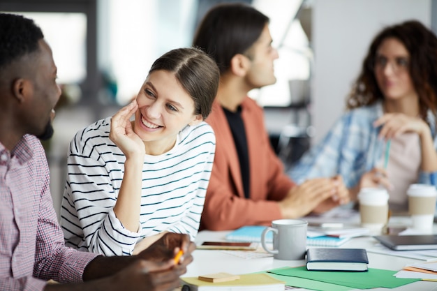 Jovem mulher falando com o colega na reunião