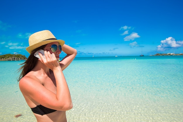 Jovem mulher falar em seu telefone na praia tropical