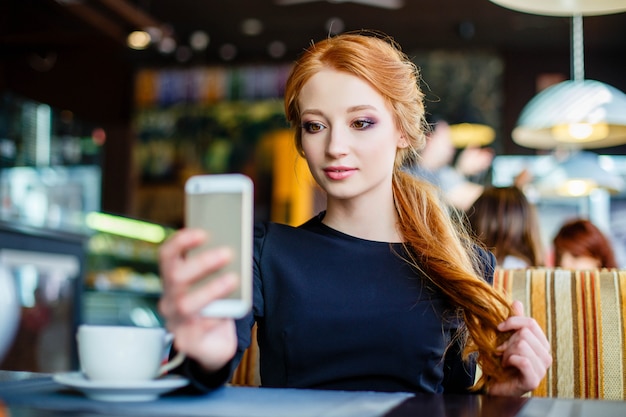 Jovem mulher fazendo auto-retrato usando smartphone