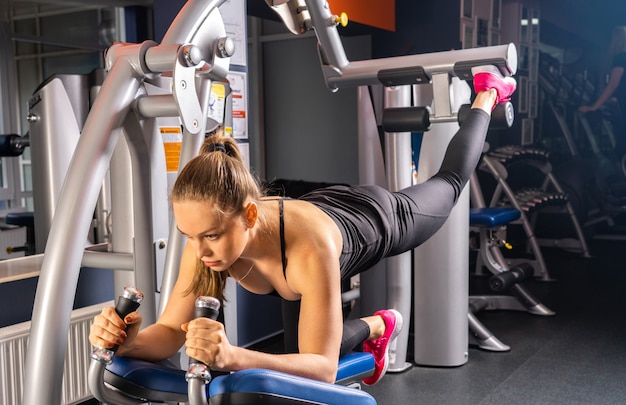 Jovem mulher fazendo esportes no ginásio, pernas e quadris exercício