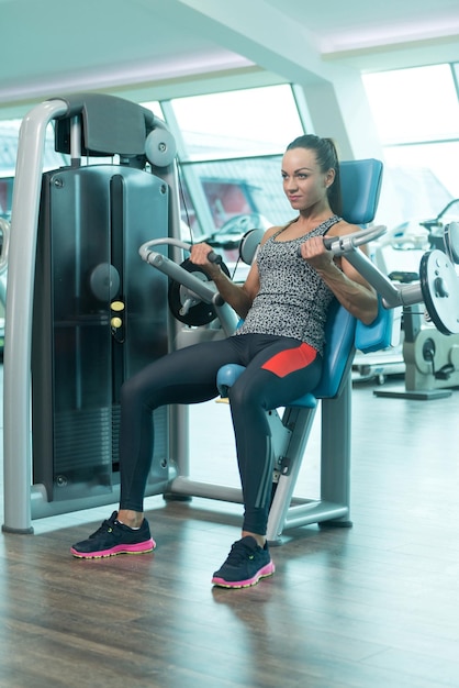 Foto jovem mulher fazendo exercício de bíceps no centro de fitness