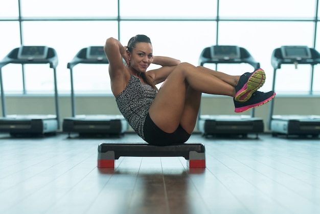 Jovem mulher fazendo exercícios abdominais no stepper