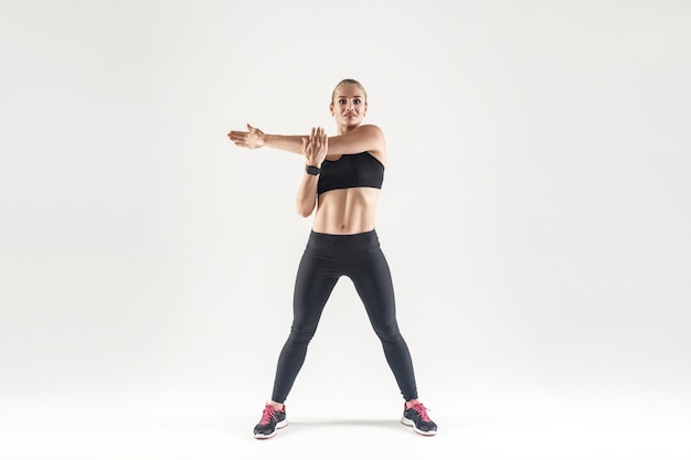 Jovem mulher fazendo exercícios aeróbicos e olhando para a câmera. Foto interna, fundo cinza