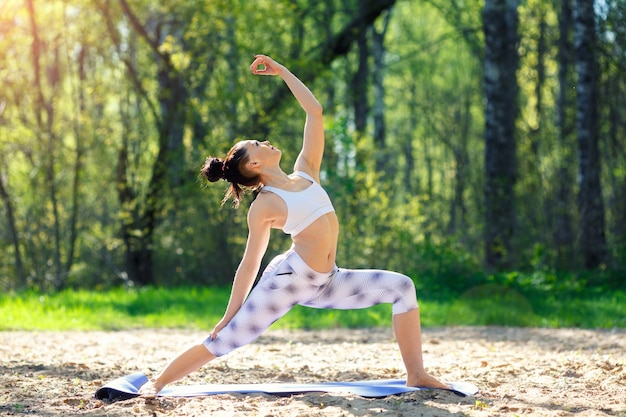 Jovem mulher fazendo exercícios de ioga no parque da cidade de verão