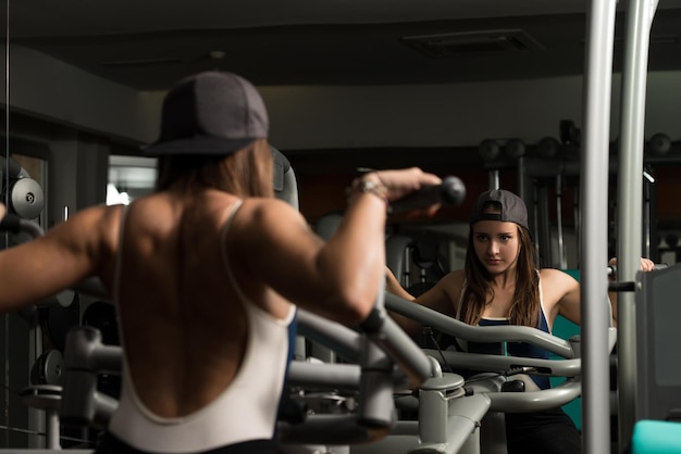 Jovem mulher fazendo exercícios de peso pesado para trás no ginásio