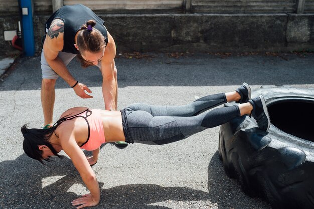 Jovem mulher fazendo flexões treinamento ao ar livre usando pneu gigante