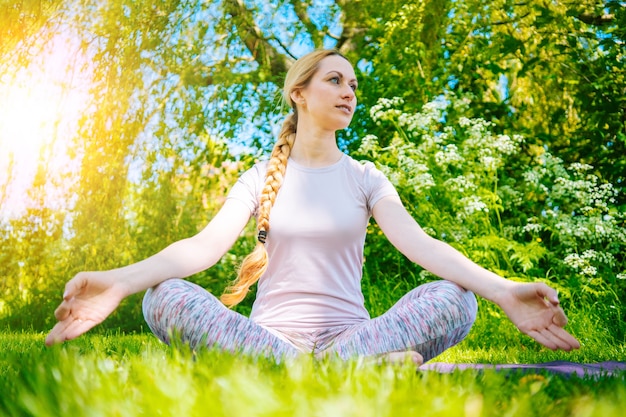 Jovem mulher fazendo ioga asana no parque. Menina, exercícios de alongamento em posição de ioga. Mulher feliz e saudável.