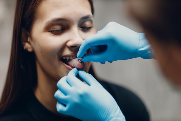 Jovem mulher fazendo piercing tonque no salão de estúdio de beleza