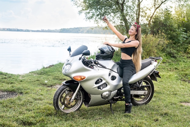 Jovem mulher fazendo selfie em uma moto ao ar livre