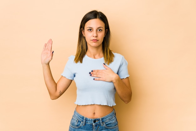 Jovem mulher fazendo um juramento, colocando a mão no peito.