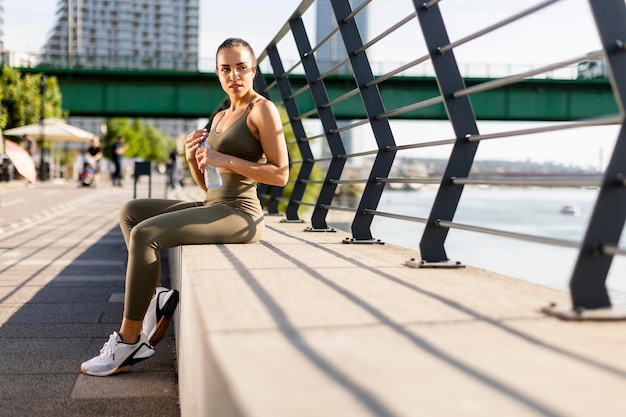 Jovem mulher fazendo uma pausa durante o exercício no passeio do rio