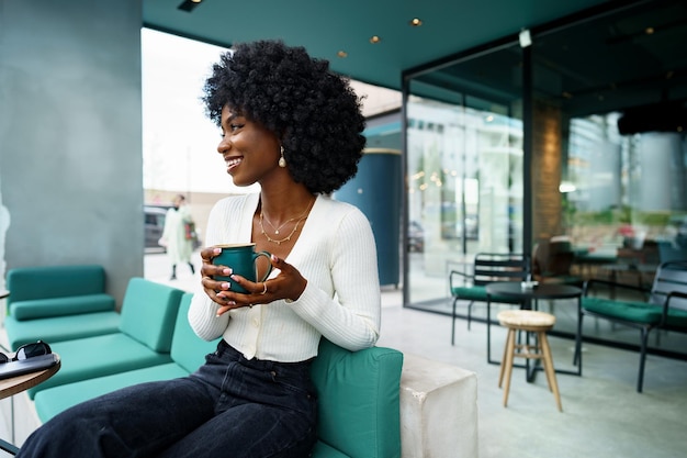 Jovem mulher fazendo uma pausa e tomando café no café