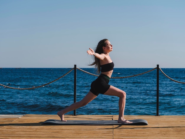 jovem mulher fazendo yoga na praia