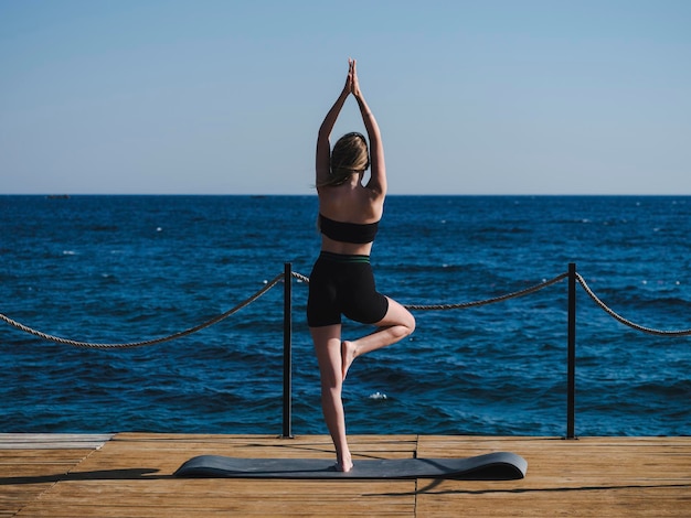 jovem mulher fazendo yoga na praia