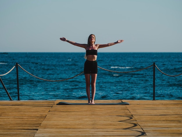 jovem mulher fazendo yoga na praia