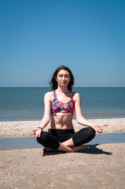 Jovem mulher fazendo yoga na praia