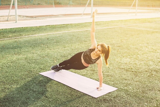 Jovem mulher fazendo yoga no estádio