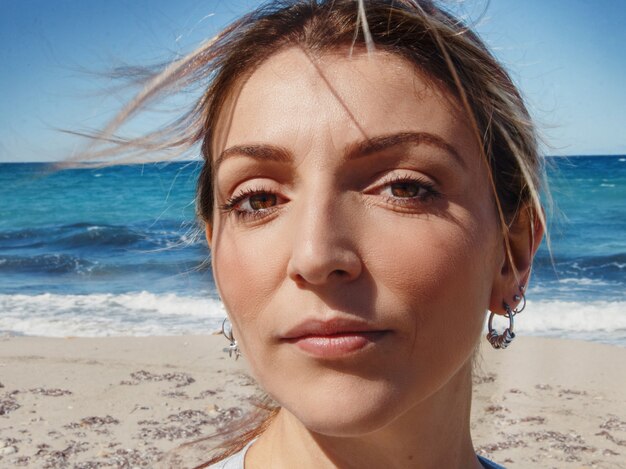 Foto jovem mulher fechando a cabeça em um dia ventoso na praia