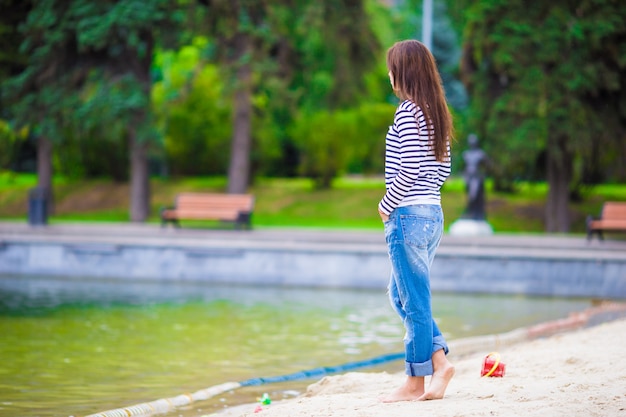 Jovem mulher feliz andando perto do lago em dia quente