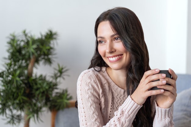 Jovem mulher feliz bebendo chá da manhã. Lindo sorriso feminino.