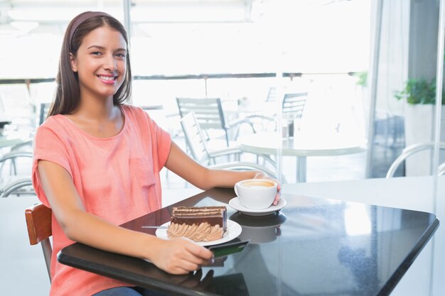 Jovem mulher feliz com bolo e café