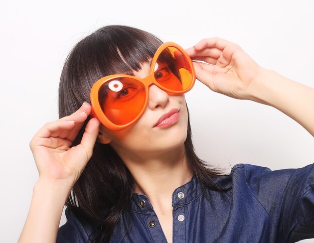 Jovem mulher feliz com grandes óculos de sol laranja