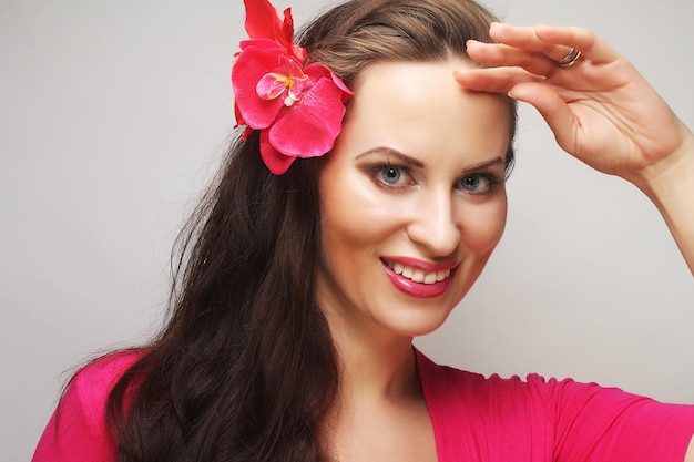 Jovem mulher feliz com uma flor rosa no cabelo