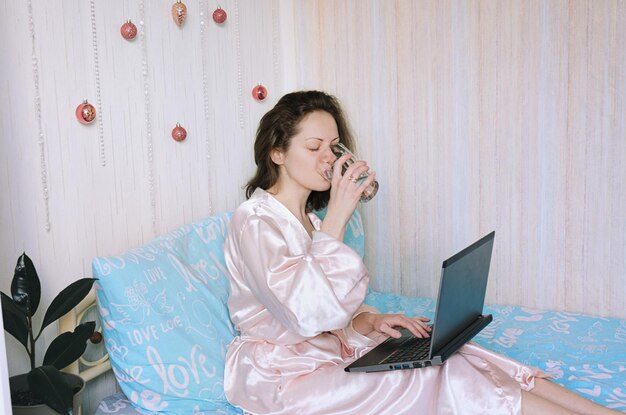 Jovem mulher feliz com uma toalha na cabeça encontra-se na cama de pijama. casa aconchegante. caderno. Rotina de beleza