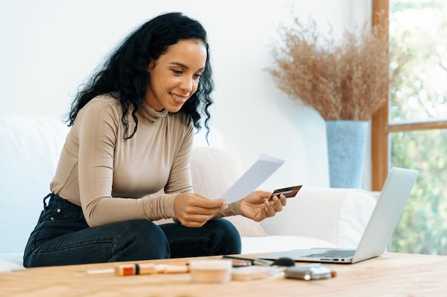 Foto jovem mulher feliz compra produtos fazendo compras on-line em casa enquanto solicita itens da internet com sistema de pagamento on-line com cartão de crédito protegido por segurança cibernética crucial da plataforma da loja on-line