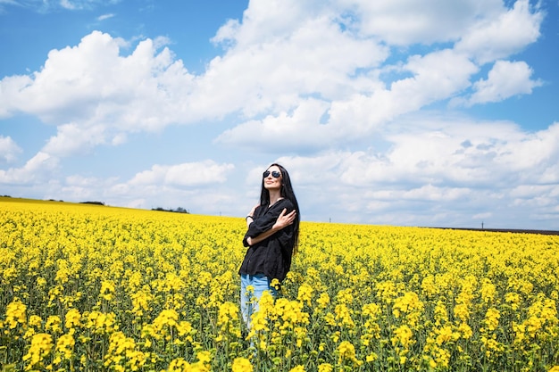 Jovem mulher feliz desfrutando de campo de canola.