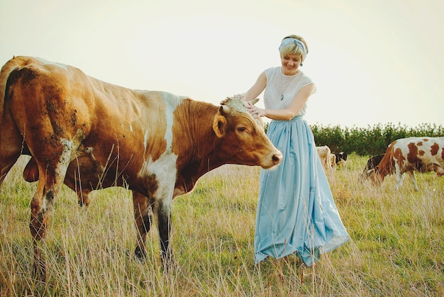 Jovem mulher feliz elegante andando na natureza, vila. Pasto, prado. vacas. Paisagem rural