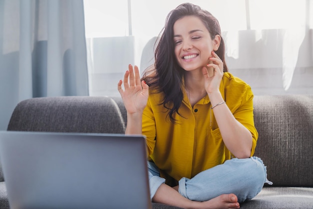 Foto jovem mulher feliz fazendo videochamada gesticulando oi para amigos